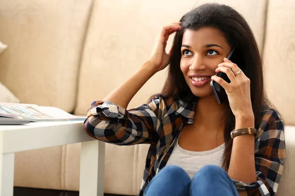 Sorrindo mulher negra segurar na mão telefone celular em casa — Fotografia de Stock