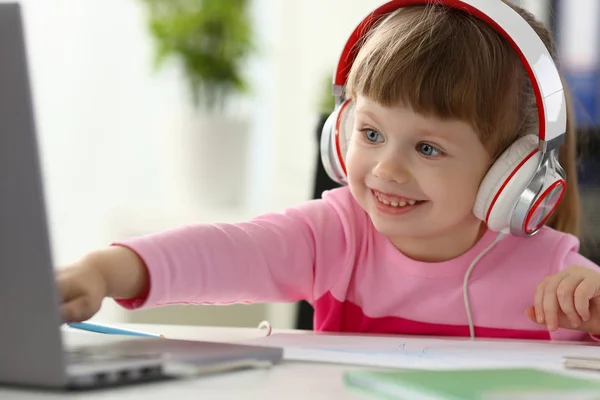 Petite fille portant des écouteurs utilisent un ordinateur mobile — Photo