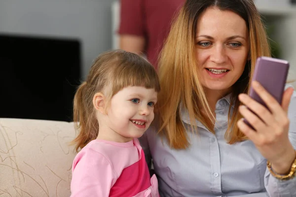 Madre y su hija pequeña usando el teléfono celular para llamar a sus hermanos — Foto de Stock