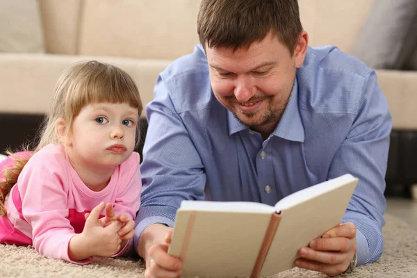 Far och dotter ligga på golvet läsning intressant bok — Stockfoto