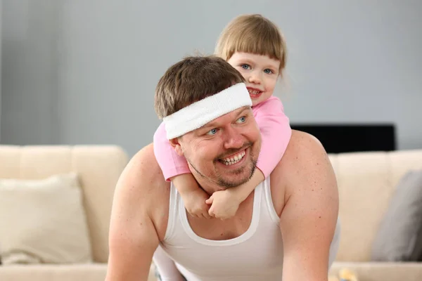 Cute little girl riding her father at home playing — Stock Photo, Image