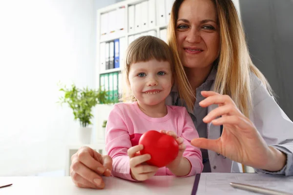 Kis kislány látogató orvos gazdaság kezében piros játék szív — Stock Fotó