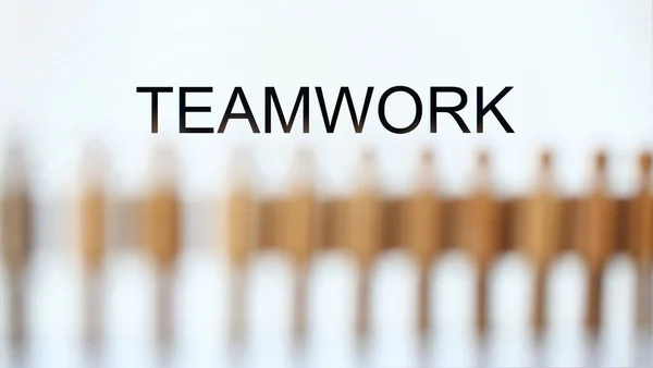 Teamwork sign above line of toy human figures