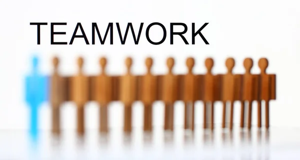 Teamwork sign above line of toy human figures