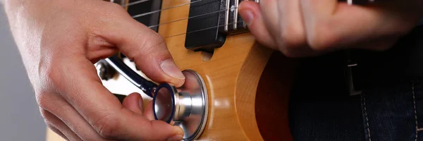 Brazos masculinos sostienen estetoscopio cabeza diagnosticando guitarra — Foto de Stock