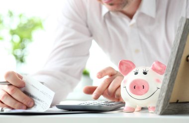 Komik güzel piggybank ve arka planda erkek iş giderleri değerlendirme