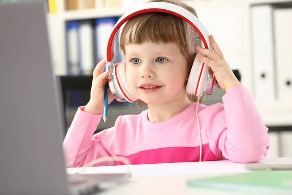 Petite fille portant des écouteurs utilisent un ordinateur mobile — Photo