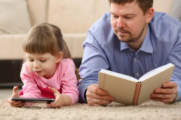 Far och dotter ligger på golvet med hjälp av mobil telefon — Stockfoto