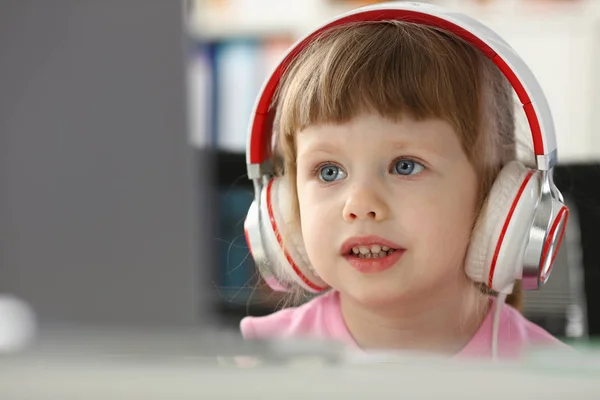 Küçük kız giyen kulaklık Mobil bilgisayar kullanımı — Stok fotoğraf
