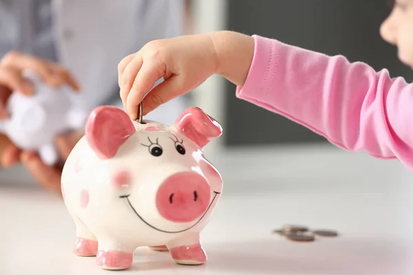 Hand van kleine meisje zetten munten in Funny Piggy Bank PIN slot — Stockfoto