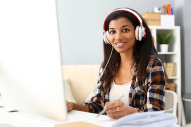 Siyah gülümseyen kadın işyerinde kulaklık giyiyor oturuyor