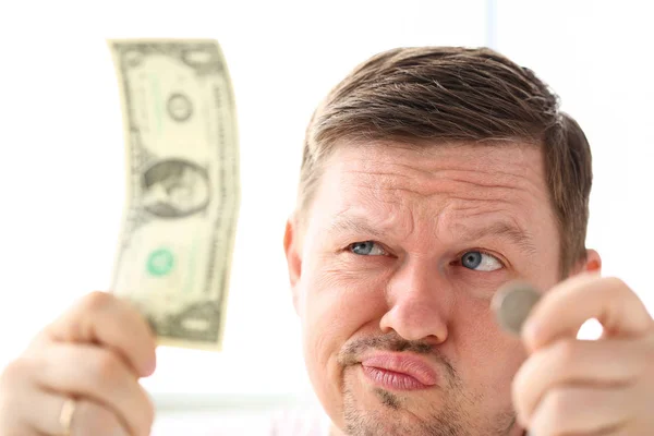 Hombre divertido sosteniendo en las manos papel y moneda moneda tratando de inventar alguna buena solución —  Fotos de Stock