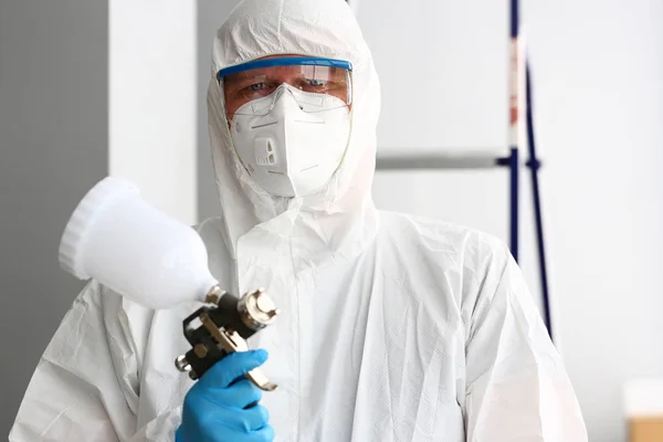 Workman hold in arm airbrush gun wearing protective suit — Stock Photo, Image