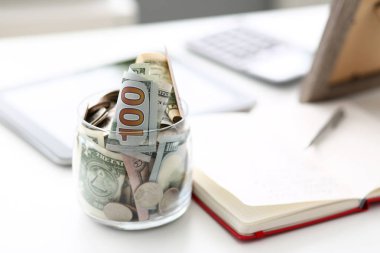 Boş çalışma masasında duran Amerikan banknotları ve sikkeleri ile dolu büyük kavanoz