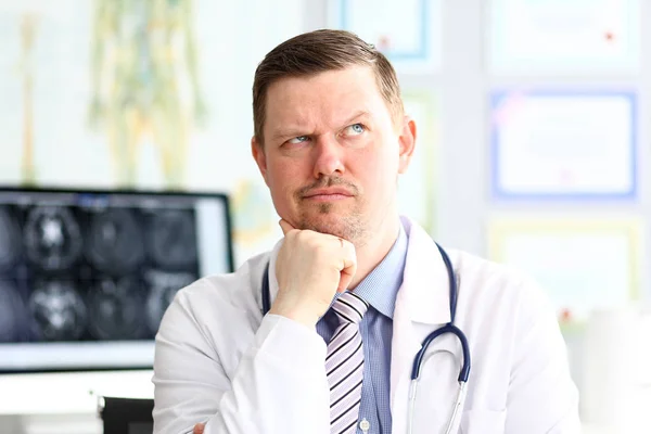 Male doctor with strange facial expression sit in his office