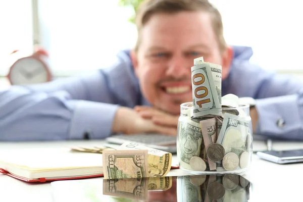 Hombre mirando frasco lleno de dinero pensando en sus oportunidades —  Fotos de Stock