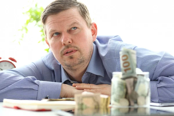 Hombre mirando frasco lleno de dinero pensando en sus deudas — Foto de Stock