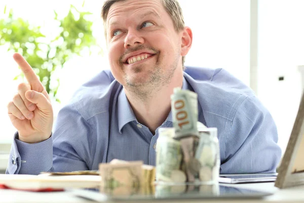 Hombre mirando frasco lleno de dinero pensando en sus oportunidades —  Fotos de Stock