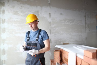 Sarı sert şapkalı erkek inşaatçı tutar