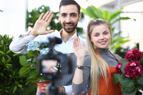 Homem e mulher blogueiro com flor acenando para câmera — Fotografia de Stock