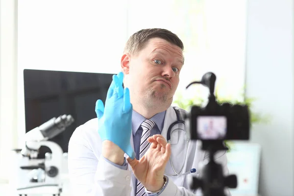 Arzt zieht an der Hand blauen Schutzanzug — Stockfoto