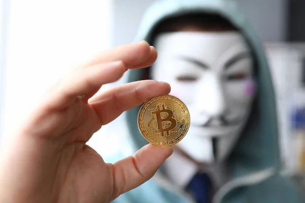 Hacker tragen anonyme Maske und halten Bitcoin in der Hand — Stockfoto