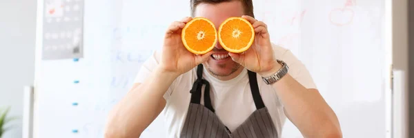 男の目としてカット オレンジの半分を保持します。 — ストック写真