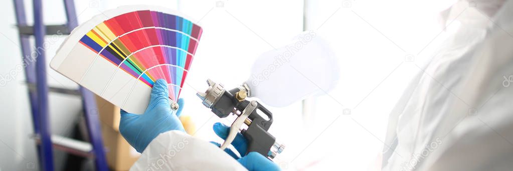 Hands of workman holding airbrush and colorful fantail picking wall