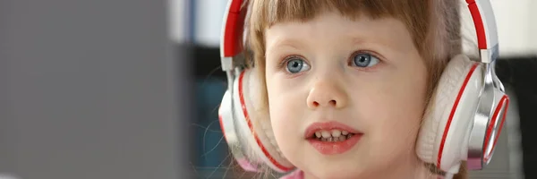 Küçük kız giyen kulaklık Mobil bilgisayar kullanımı — Stok fotoğraf