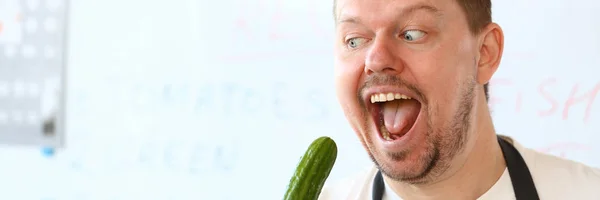 Professionele chef-kok die groene biologische komkommer eet — Stockfoto