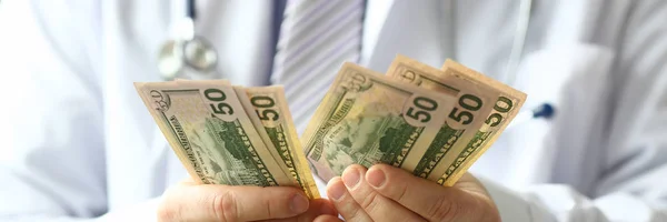 Mão masculina de médico hald dólar em dinheiro na mão — Fotografia de Stock
