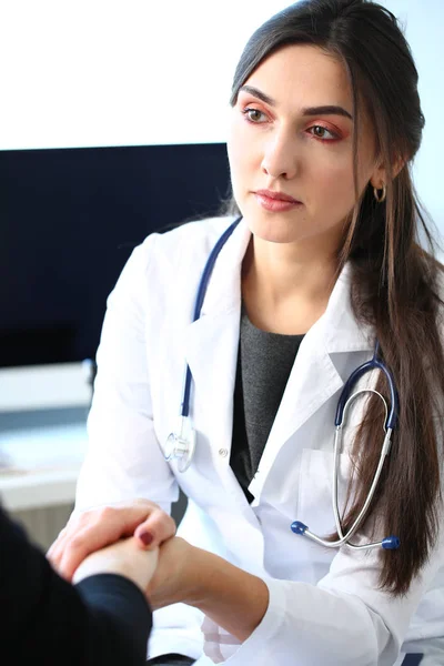 Junge Ärztin hält kranke Patientin an der Hand — Stockfoto