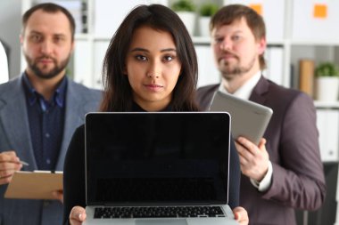 Genç başarılı businesslady portresi ofiste dizüstü bilgisayar ve iki iş adamları tutun