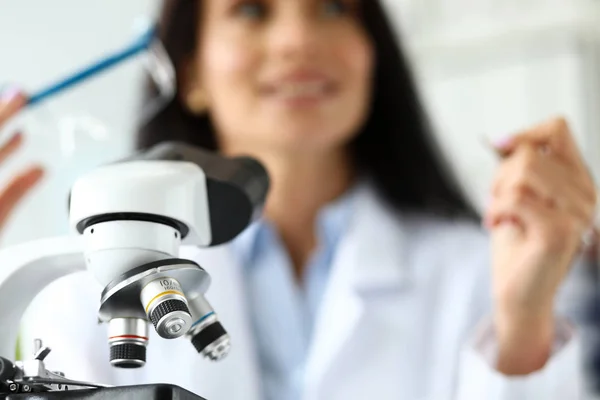 Объектив научного микроскопа с женщиной-аналитиком на заднем плане — стоковое фото
