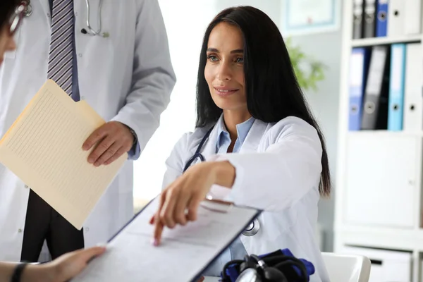 Красивая белая женщина-терапевт указывает пальцем в анкете — стоковое фото