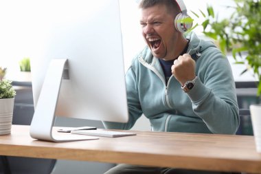 Bilgisayar monitöründe çığlık atan adam oturuyor