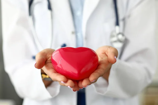 Kadın kardiyolog kollarında kırmızı oyuncak kalp tutarak — Stok fotoğraf