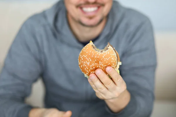 Leende man hålla färska hamburgare i hand bakgrund — Stockfoto