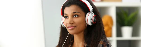 Schwarz lächelnde Frau sitzt mit Kopfhörern am Arbeitsplatz — Stockfoto