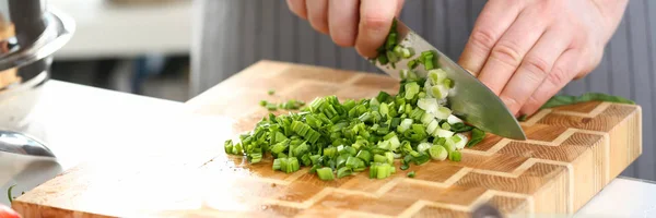 Macho mano cocinero mantenga cuchillo y cortar cebolla verde — Foto de Stock