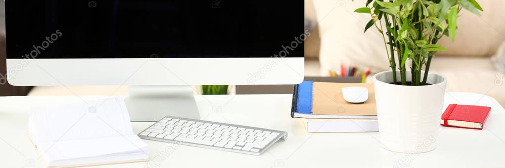 Empty silver computer at worktable with sofa in background