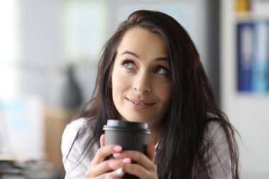 Güzellik işkadını elinde siyah kağıt bardak tutuyor.