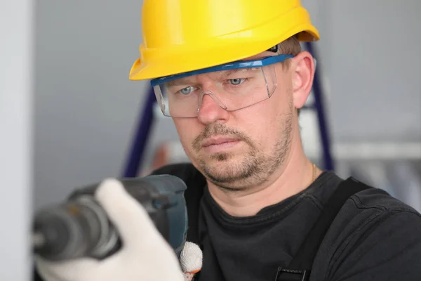 Masculino adulto trabalhador em amarelo helmrt hol broca elétrica na mão . — Fotografia de Stock