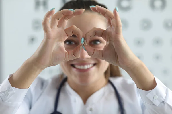 Kobieta okulista pokazuje okulary na palcach — Zdjęcie stockowe