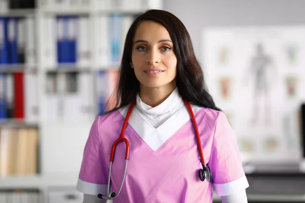 Beautiful woman doctor in uniform stands in office