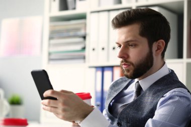 Ciddi sakallı ofis çalışanı gelir mesajını okuyor.