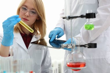 Test tüpüne bakan genç laboratuvar asistanı.