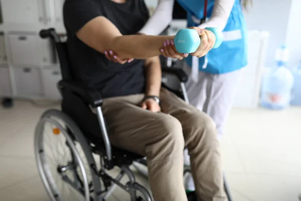 Человек в инвалидном кресле протягивает руку гантели — стоковое фото
