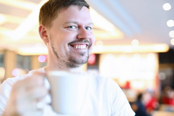 Sonriente hombre sentado en la cafetería con gran taza de café —  Fotos de Stock