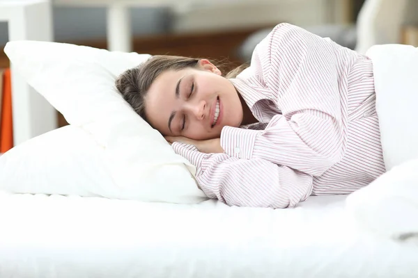 Ευτυχισμένο κορίτσι με πιτζάμες ξαπλώνει στο κρεβάτι και κλείνει τα μάτια της — Φωτογραφία Αρχείου